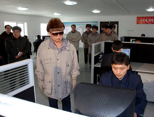 Gente que mira a Kim Jong-Il mientras él mira un ordenador.