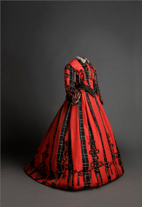 Traje. 1865 - 1868. En satén de color negro y coral con decoración de aplicación de pasamanería (Museo del Traje. CIPE)